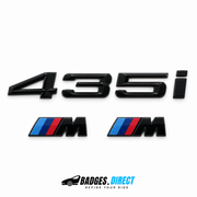 Gloss-black BMW 435i rear lettering and two M wing badges with coloured stripes.